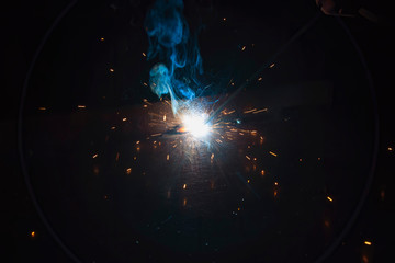 The process of manual welding. Industrial welding of iron construction elements.  Splashes of hot metal.