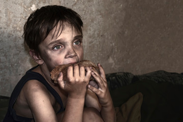 Child homeless, beggar eat a piece of black bread (concept of war, poverty, crisis)