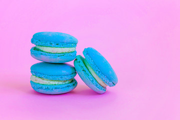 Sweet almond colorful unicorn blue macaron or macaroon dessert cake isolated on trendy pink pastel background. French sweet cookie. Minimal food bakery concept Copy space
