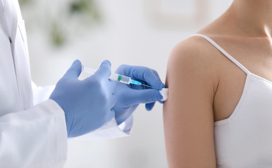 Doctor giving injection to patient in hospital, closeup. Vaccination concept