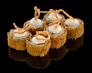 Hot Fried Uramaki Sushi roll with sauce fried onion on top isolated on black background with reflection