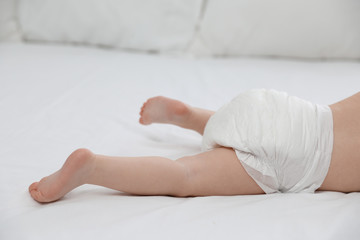 Cute little baby in diaper on bed, closeup