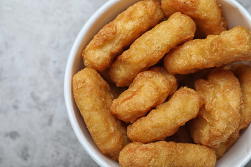 Bucket with tasty chicken nuggets on grey table, top view
