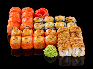 Assorted Uramaki Sushi set with ginger and wasabi isolated on black background with reflection