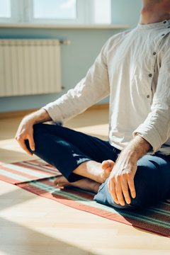 Man practice yoga. Young attractive male doing breathing exercises. Guy meditating at home along during the pandemic. Relaxation and resting concept for isolation. Slide shot.