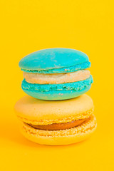 Sweet almond colorful unicorn blue yellow macaron or macaroon dessert cake isolated on trendy yellow modern fashion background. French sweet cookie. Minimal food bakery concept Copy space