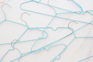  Flat lay set of blue hangers on white marble. Many colored hangers lying chaotically, minimal concept