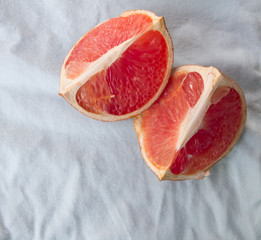 Quarters flat layout of grapefruit slices on marble and blue loaf close-up, top view with copy space