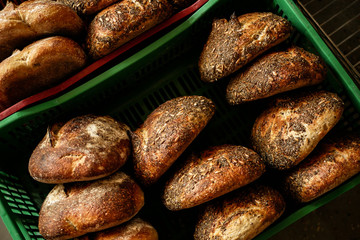Freshly baked sour dough bread loafs left to cool down at the artesanal bakery in the plastic box. Bread's crust covered with chia seeds and sunflower seeds.