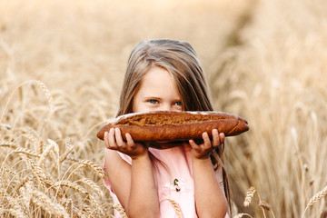 Happy little girl child in wheat cereal field in summer. Children with bread. Little girl in cereal...