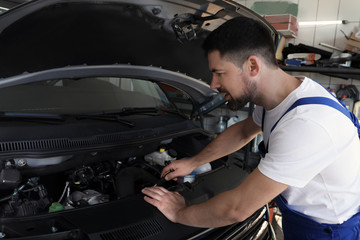 Plakat Professional auto mechanic fixing modern car in service center
