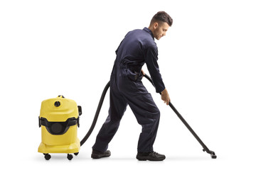Janitor in a uniform cleaning the floor with a vacuum cleaner