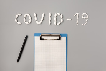 COVID-19 flu epidemic. The inscription Covid-19 of pills.  Tablets, notepad and pen on a gray background, Flat lay, copy space. Temperature measurment