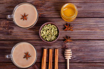 Glass cups of traditional indian chai masala tea on a tray with ingredients