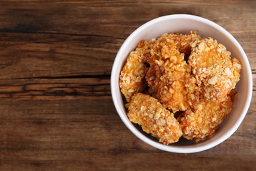 Bucket with yummy nuggets on wooden table, top view. Space for text