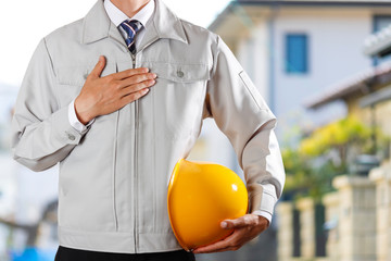 ヘルメットを持った作業服の男性