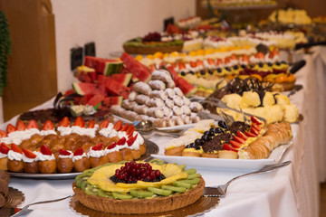 buffet with sweets. fruits and other sweets on dessert table. Rows of tasty looking desserts in beautiful arrangements. Sweets on banquet table - picture taken during catering event