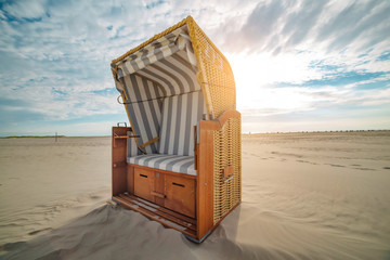 Evening close up view of Roofed wicker beach chairs on white sand beach.