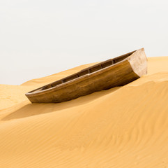 
empty wooden boat stuck in the sand in the middle of the desert