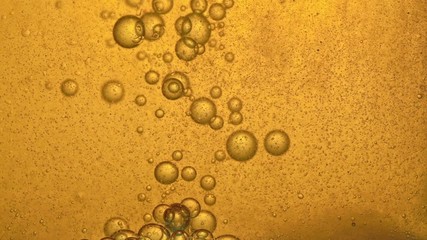 Fuel, oil, yellow golden hue, with moving bubbles, up and down, in the glass vessel of the laboratory. Copy space. - Powered by Adobe