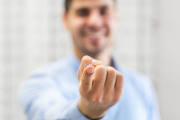 Happy guy holding contact eye lenses, selective focus