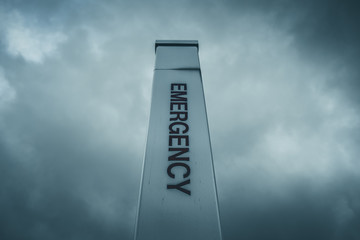 Isolated Emergency sign pole with moody sky background. Hospital alert emergency sign - 348353475
