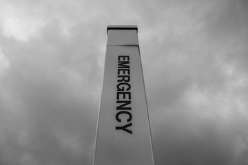 Isolated Emergency sign pole with moody sky background. Hospital alert emergency sign - 348353486