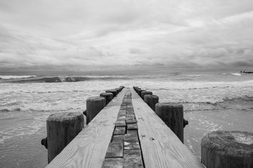 Isolated pier jetty with ocean and sky background. Waves crashing on beach wooden jetty pier.  - 348353889