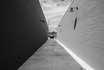 Street photography of abstract long alleyway. Pathway between two buildings with red brick wall...