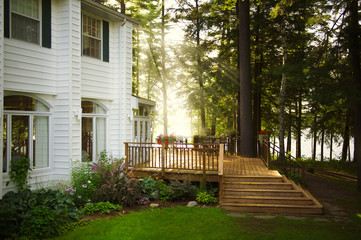 Sun rays illuminating the wooden patio of a cottage resort in Muskoka lakes in Ontario. On the patio there are outdoor furniture.