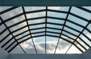Modern glass roof with steel grid frames. Skylight rooftop window with symmetrical grid steel beams. Architectural detail and design on glass rooftop - 348354277