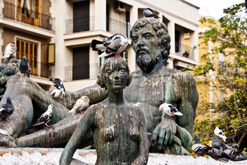 A statue in a public square in Valencia covered in pigeon feces, marring the rock.