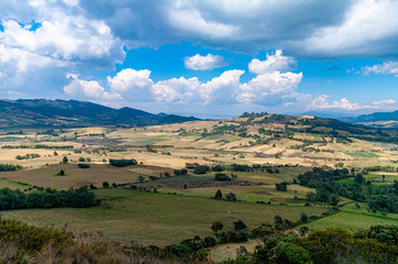 Savanna mountains with crops and clouds.
