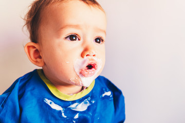 Baby laughing while trying a yogurt, isolated on white.