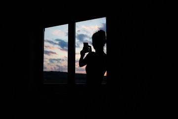 woman silhouette watching sunset from window quarantine concept