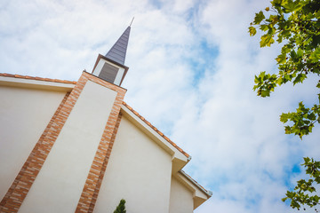 Building facade of a traditional American Protestant church with clock tower and blue sky.