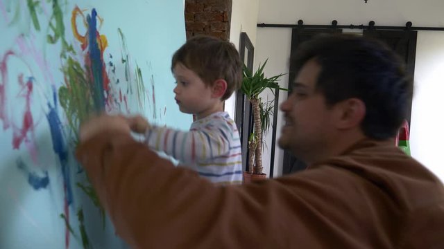 father and son paint on the wall during quarantine
