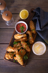 Chicken wings on serving board and glass of beer. View from above, top view