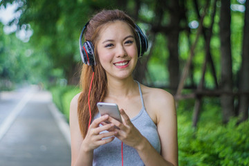 Beautiful young woman with head phone listening music in the park