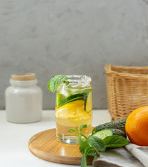 Cold refreshing water with cucumber, mint and lemon in a glass with a sugar rim on a gray background