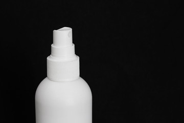 White bottle of antiviral spray for skin of hands on a black background