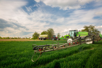 Tractor spraying pesticides, fertilizing on the vegetable field with sprayer at spring, fertilization concept