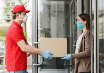 Girl opens door and takes box from the courier, in protective mask and gloves