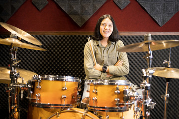 Fototapeta na wymiar Portrait of a young Asian woman and a drum in a music practice room