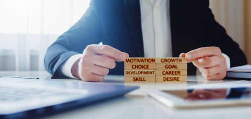 Personal Development Concept. a man lays on the table wooden blocks with the words motivation, growth, skill, goal, choice