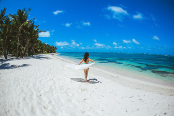 Woman enjoying sunny day on the tropical caribbean sandy beach landscape with turquoise sea and blue sky 