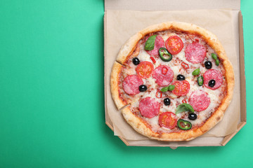 Delicious pizza Diablo in cardboard box on green background, top view. Space for text