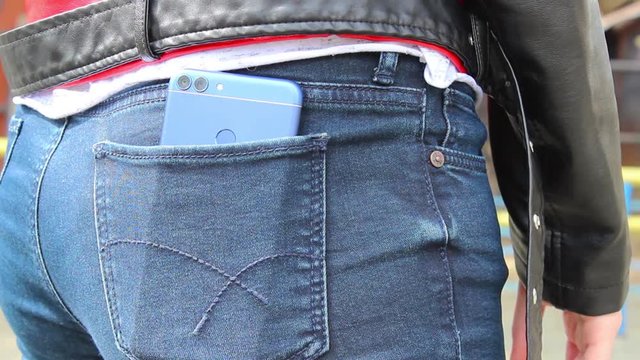 The girl shoves the smartphone into the back pocket of her jeans.