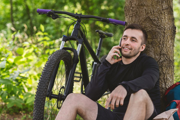 Plakat Close up of young guy talking by phone under tree