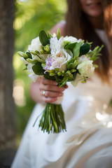 The bride holds a bouquet in her hands. Wedding in the tropics. Palm tree on the background. No focus, blurred.